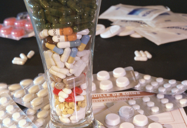 Plaquettes de médicaments et verre rempli de médicament placés sur une table