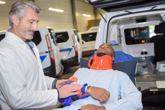 Une personne blessée sur un brancard, accompagné d'un professionnel de santé 