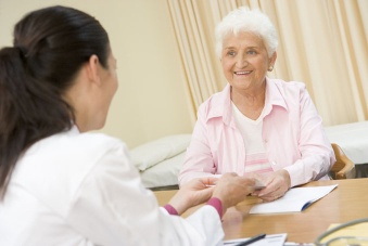 Photo présentant une patiente âgée avec des vêtements clairs en face d'un médecin femme en blouse blanche vue de dos